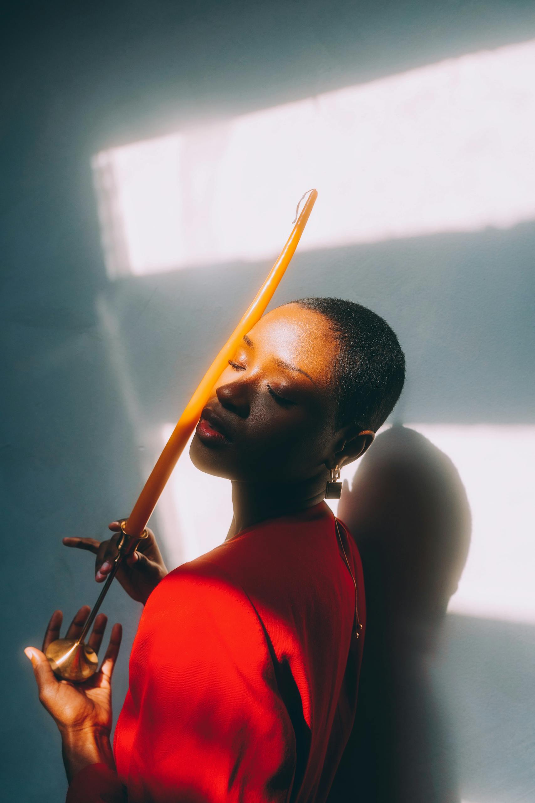 A creative portrait of a woman posing with a candle in dramatic lighting and shadows.